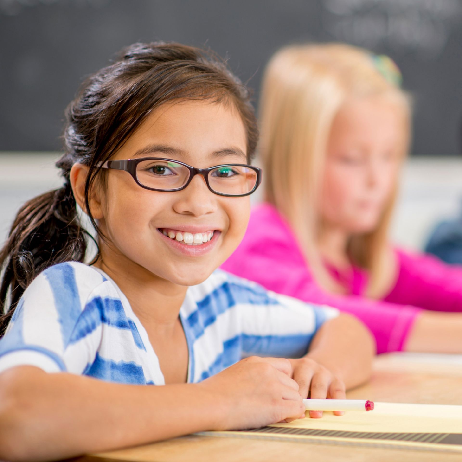 Fille porte des lunettes et sourit en classe